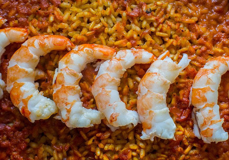 Primer plano de un arroz con unas gambas encima.