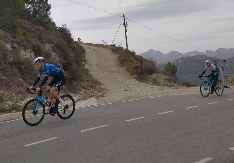 Dos ciclistas subiendo por una carretera.
